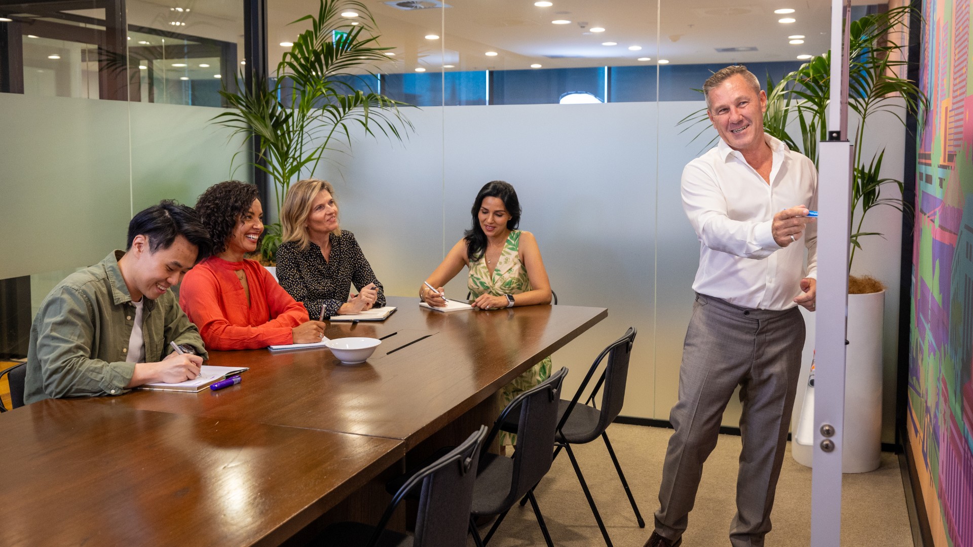 group of people in a workshop, man writing on whiteboard and presenting 