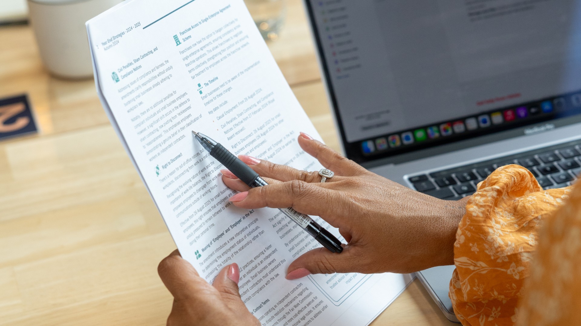 lady referring to document while working on computer