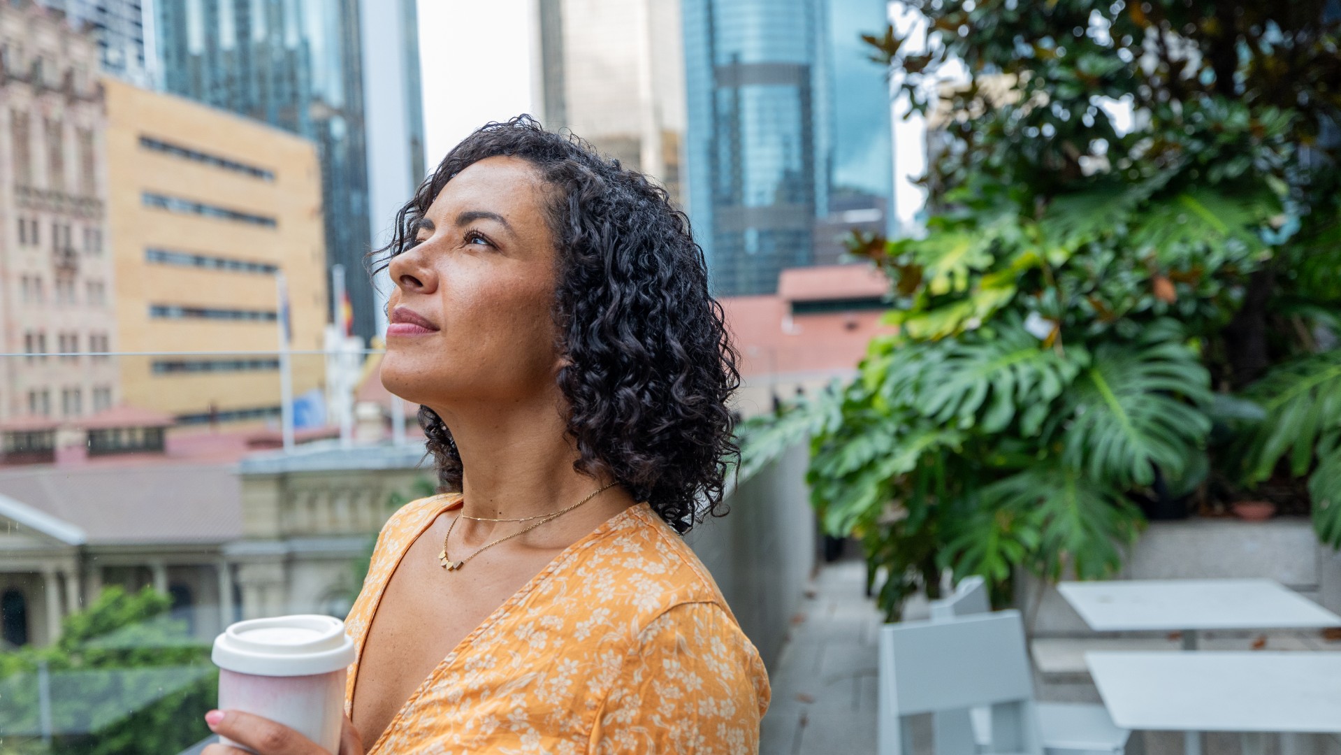 women standing on city balcony, looking up into the sky mindfully