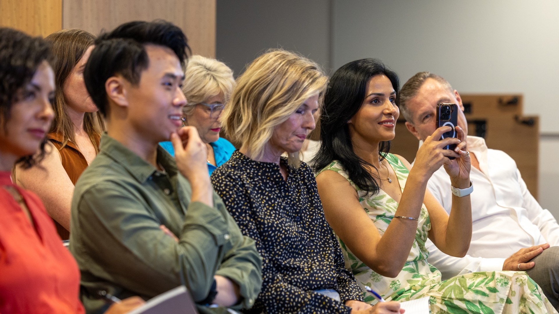 Woman seated in crowd recording Event